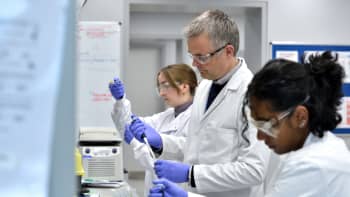 Three scientists pipetting in a laboratory.